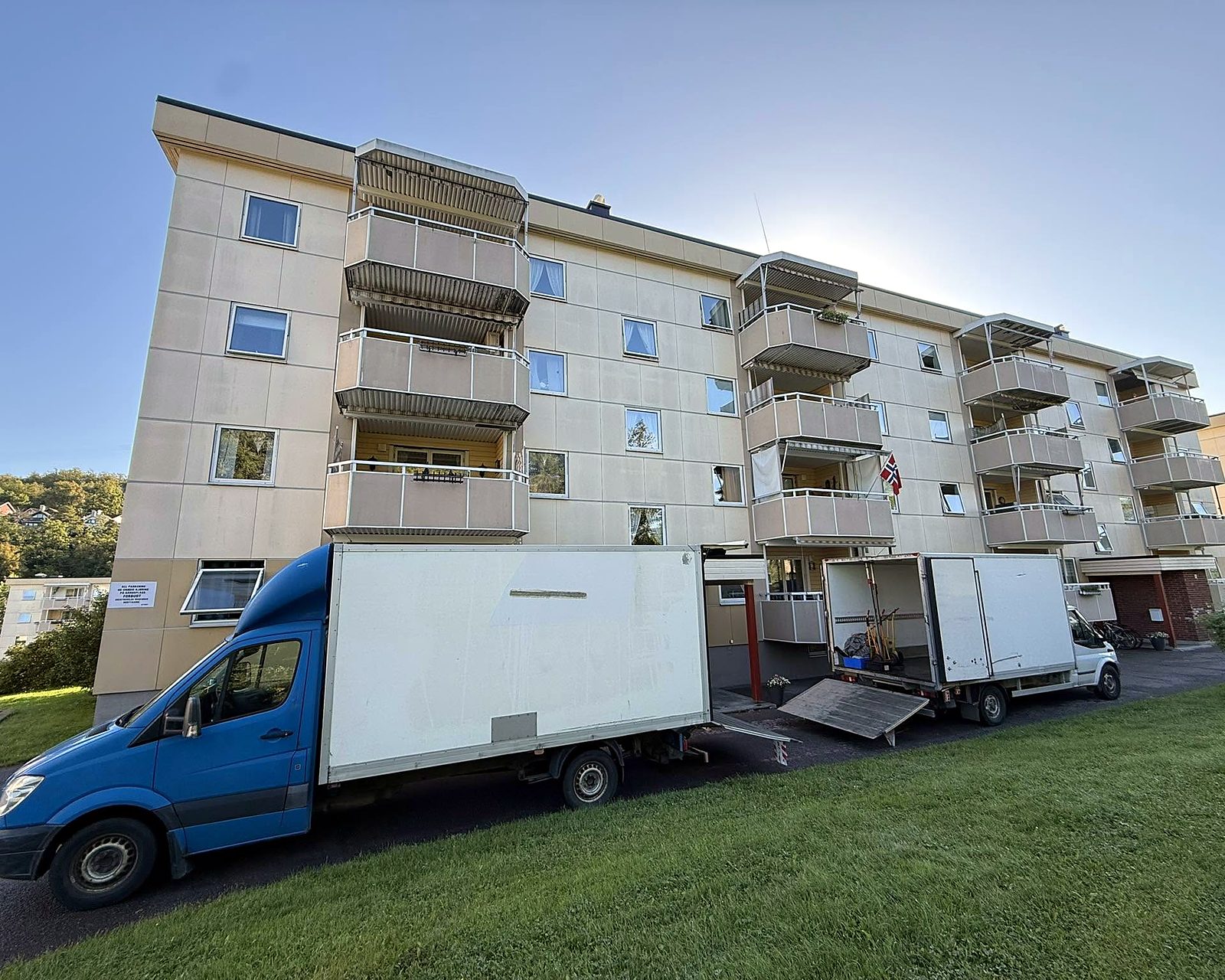 To flyttebiler fra Flyttebyrået Jarlsberg parkert ved en boligblokk